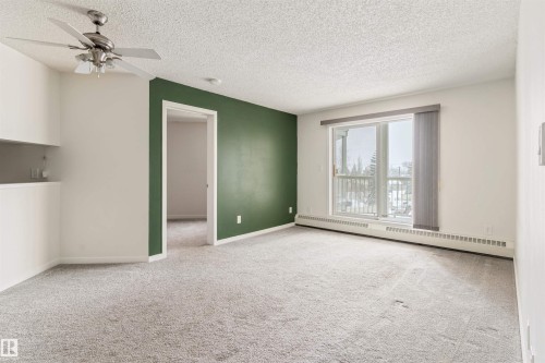 Empty room featuring a baseboard radiator, ceiling fan, carpet, and a textured ceiling - 312 11620 9A Avenue, Edmonton, AB - Indoor Photo Showing Other Room