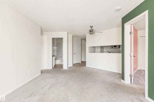 Unfurnished living room with carpet flooring, ceiling fan, and a textured ceiling - 312 11620 9A Avenue, Edmonton, AB - Indoor Photo Showing Other Room