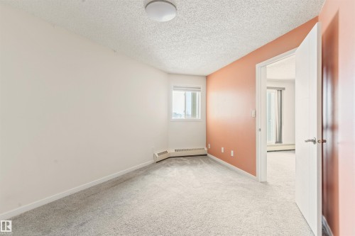 Spare room featuring light carpet, baseboard heating, and a textured ceiling - 312 11620 9A Avenue, Edmonton, AB - Indoor Photo Showing Other Room