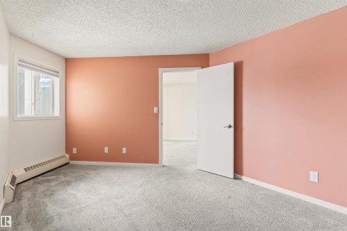 Spare room featuring baseboard heating, light colored carpet, and a textured ceiling - 312 11620 9A Avenue, Edmonton, AB - Indoor Photo Showing Other Room