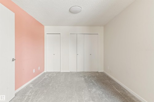 Unfurnished bedroom with carpet, two closets, and a textured ceiling - 312 11620 9A Avenue, Edmonton, AB - Indoor Photo Showing Other Room