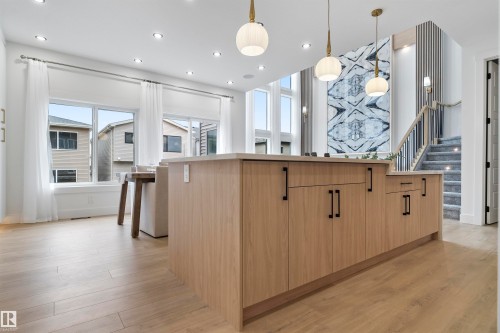 Kitchen with a large island, light wood finish cabinetry, light wood-style flooring, modern cabinets, and pendant lighting - 7026 Kiviaq Crescent, Edmonton, AB - Indoor Photo Showing Kitchen