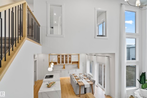 Living area featuring light wood-style flooring, hanging lights, and a high ceiling - 7026 Kiviaq Crescent, Edmonton, AB - Indoor Photo Showing Other Room