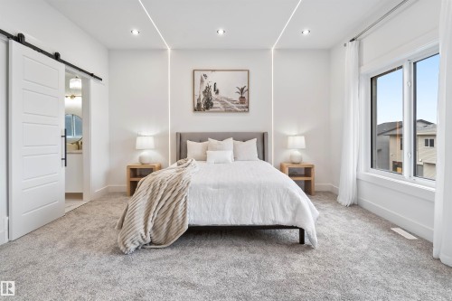 Bedroom with a barn door, carpet floors, recessed lighting, and connected bathroom - 7026 Kiviaq Crescent, Edmonton, AB - Indoor Photo Showing Bedroom