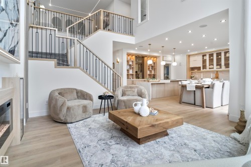 Living room featuring recessed lighting, light wood-style floors, a glass covered fireplace, and a high ceiling - 7026 Kiviaq Crescent, Edmonton, AB - Indoor Photo Showing Living Room With Fireplace