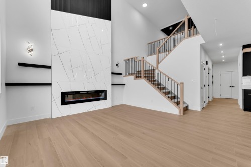 Unfurnished living room featuring a high ceiling, a tile fireplace, light wood-style flooring, and recessed lighting - 741 Astoria Way, Devon, AB - Indoor With Fireplace