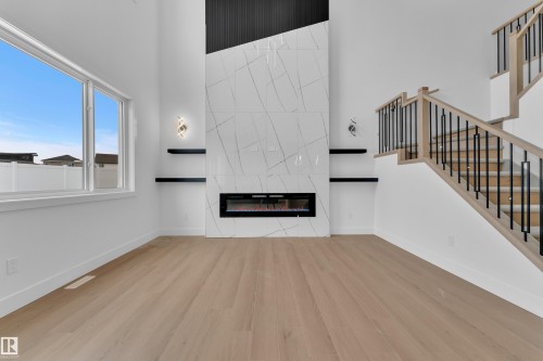 Unfurnished living room with a high ceiling, light wood-style floors, and a fireplace - 741 Astoria Way, Devon, AB - Indoor With Fireplace