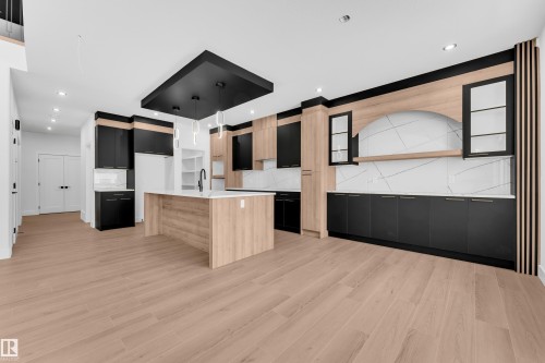 Kitchen with dual tone cabinetry, modern cabinets, a center island with sink, light stone countertops, and light wood-type flooring - 741 Astoria Way, Devon, AB - Indoor Photo Showing Kitchen