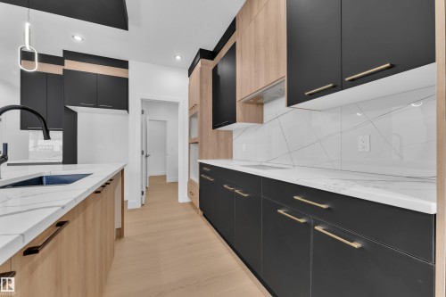 Two tone kitchen featuring dual tone cabinetry, light stone counters, modern cabinets, pendant lighting, and backsplash - 741 Astoria Way, Devon, AB - Indoor Photo Showing Kitchen