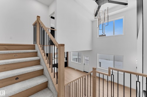 Stairway with wood finished floors, a high ceiling, and hanging lights - 741 Astoria Way, Devon, AB - Indoor Photo Showing Other Room
