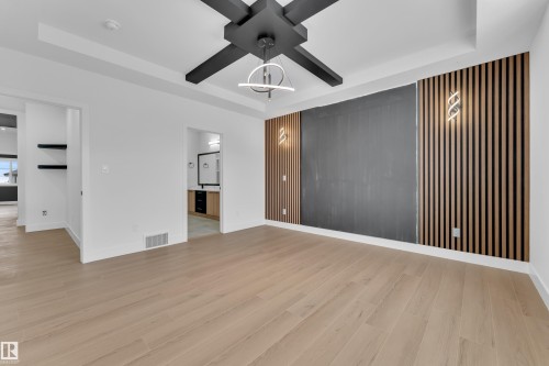 Unfurnished living room with a tray ceiling, ceiling fan, light wood-style floors, and an accent wall - 741 Astoria Way, Devon, AB - Indoor Photo Showing Other Room