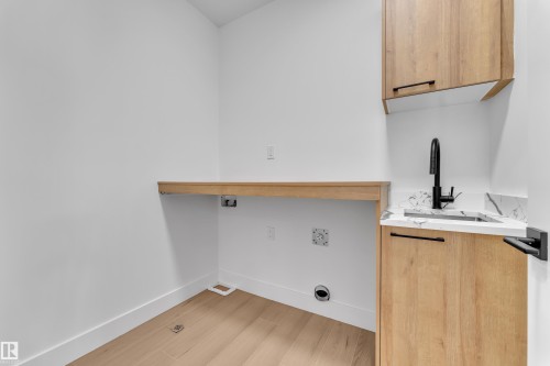 Laundry area featuring light wood-type flooring and cabinet space - 741 Astoria Way, Devon, AB - Indoor Photo Showing Other Room