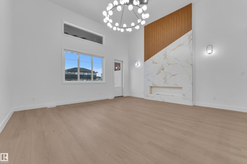Spare room with hanging lights, a high ceiling, and light wood-type flooring - 215 Basin Court, Leduc, AB - Indoor Photo Showing Other Room