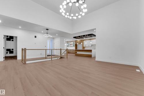 Unfurnished living room with suspended lighting, light wood finished floors, and a high ceiling - 215 Basin Court, Leduc, AB - Indoor Photo Showing Other Room