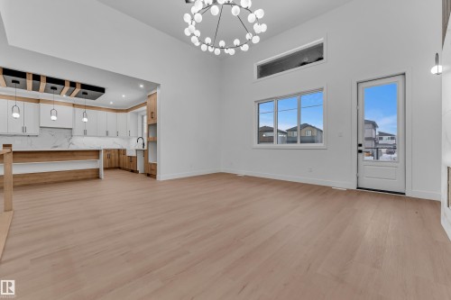 Unfurnished living room featuring suspended lighting, light wood-style flooring, and a high ceiling - 215 Basin Court, Leduc, AB - Indoor Photo Showing Other Room