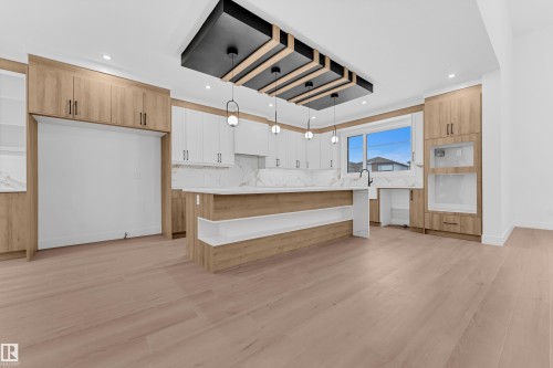Two tone kitchen with a center island, light wood finished floors, two tone cabinetry, tasteful backsplash, and hanging light fixtures - 215 Basin Court, Leduc, AB - Indoor Photo Showing Kitchen