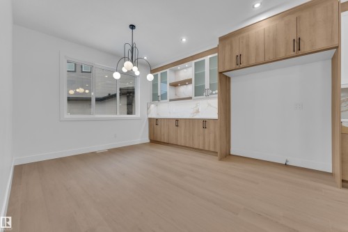 Unfurnished dining area with light wood-style flooring and a chandelier - 215 Basin Court, Leduc, AB - Indoor