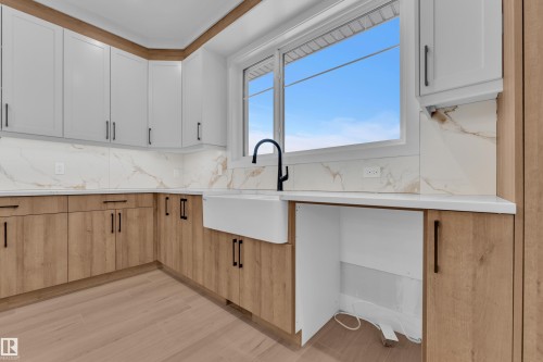 Kitchen with light wood-style floors, two tone cabinetry, light stone counters, and decorative backsplash - 215 Basin Court, Leduc, AB - Indoor Photo Showing Kitchen