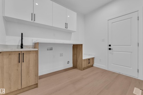 Laundry area with light wood finished floors, cabinet space, and washer hookup - 215 Basin Court, Leduc, AB - Indoor Photo Showing Other Room