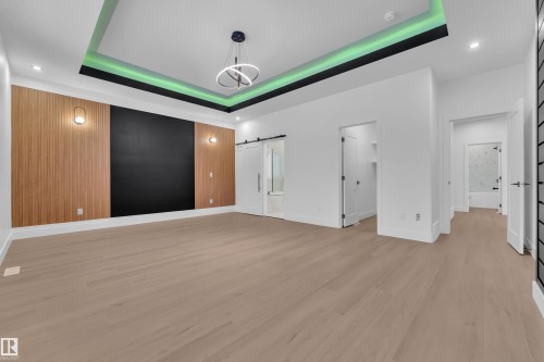 Unfurnished bedroom with a spacious closet, a barn door, recessed lighting, ensuite bathroom, and light wood finished floors - 215 Basin Court, Leduc, AB - Indoor Photo Showing Other Room