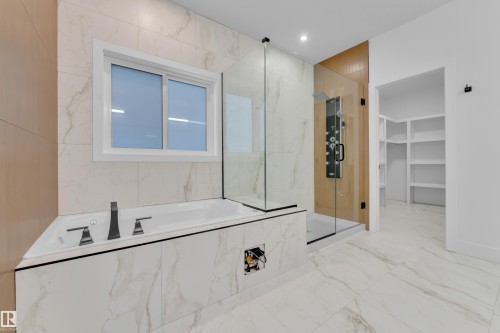 Bathroom with a marble finish shower, a garden tub, recessed lighting, a spacious closet, and light marble finish floors - 215 Basin Court, Leduc, AB - Indoor Photo Showing Bathroom