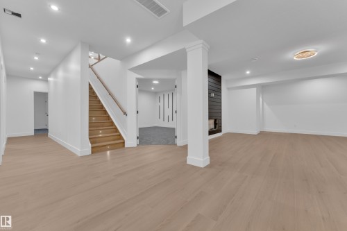 Finished basement featuring recessed lighting, a large fireplace, and light wood-type flooring - 215 Basin Court, Leduc, AB - Indoor Photo Showing Other Room