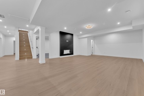 Unfurnished living room featuring light wood-style flooring, recessed lighting, and a large fireplace - 215 Basin Court, Leduc, AB - Indoor Photo Showing Other Room