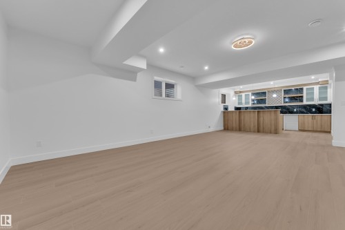 Unfurnished living room with light wood-style flooring, recessed lighting, and bar - 215 Basin Court, Leduc, AB - Indoor