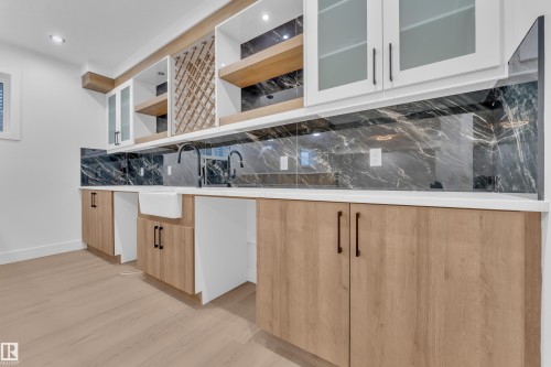 Kitchen with glass fronted cabinets, decorative backsplash, light wood-style flooring, recessed lighting, and light wood finish cabinets - 215 Basin Court, Leduc, AB - Indoor