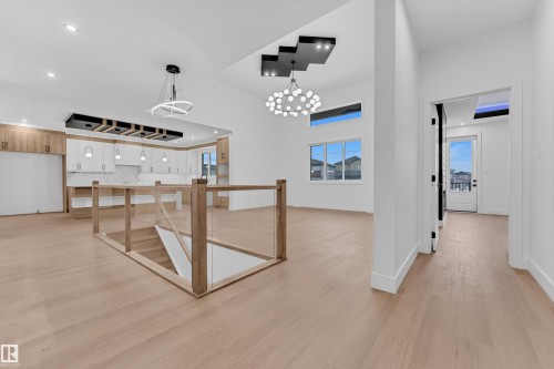 Corridor featuring light wood-style flooring and hanging lights - 215 Basin Court, Leduc, AB - Indoor Photo Showing Other Room