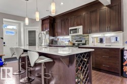 Kitchen with a center island with sink, a kitchen bar, stainless steel appliances, and healthy amount of natural light - 