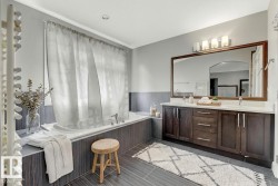 Full bath featuring double vanity, a garden tub, and wainscoting - 