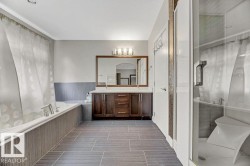 Full bath featuring double vanity, a garden tub, a wainscoted wall, and a stall shower - 