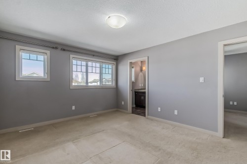 Unfurnished bedroom featuring ensuite bath, light colored carpet, and a textured ceiling - 1669 Hammond Crescent, Edmonton, AB - Indoor Photo Showing Other Room
