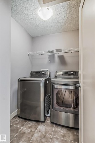 Laundry area featuring a textured ceiling, washing machine and clothes dryer, and light tile patterned floors - 1669 Hammond Crescent, Edmonton, AB - Indoor Photo Showing Laundry Room