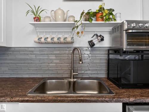 Kitchen view of open shelves, black microwave, and backsplash - 4603 32 Avenue, Edmonton, AB - Indoor Photo Showing Kitchen With Double Sink