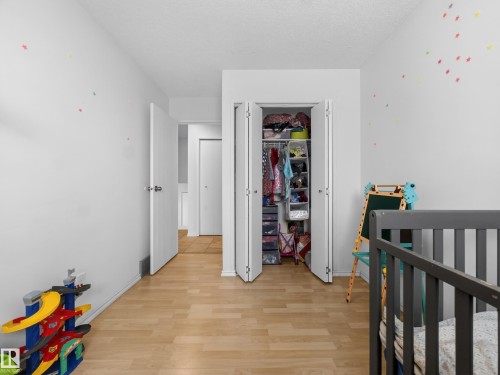 Bedroom with a crib, light wood-style floors, a closet, and a textured ceiling - 4603 32 Avenue, Edmonton, AB - Indoor Photo Showing Other Room