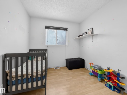 Bedroom with light wood-style floors, a textured ceiling, and a nursery area - 4603 32 Avenue, Edmonton, AB - Indoor Photo Showing Bedroom