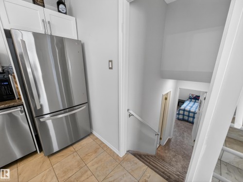 Kitchen featuring light colored carpet, stainless steel appliances, light tile patterned floors, and white cabinets - 4603 32 Avenue, Edmonton, AB - Indoor