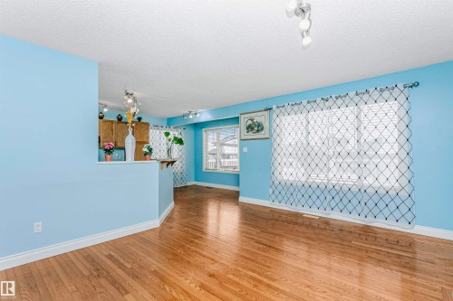 Unfurnished living room with track lighting, a textured ceiling, and wood finished floors - 607 Windross Crescent, Edmonton, AB - Indoor