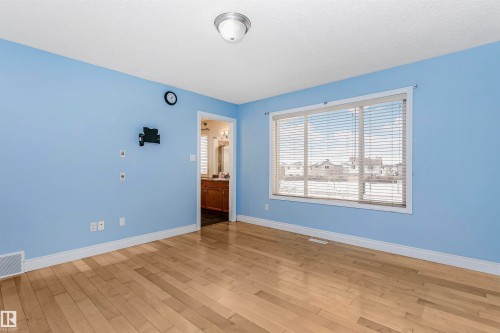 Unfurnished bedroom featuring light wood-style flooring, connected bathroom, and a textured ceiling - 607 Windross Crescent, Edmonton, AB - Indoor Photo Showing Other Room