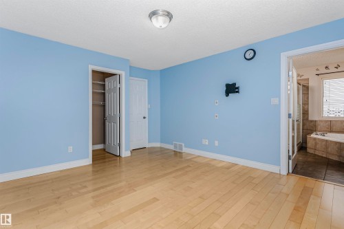 Unfurnished bedroom featuring a textured ceiling, light wood-style floors, and a spacious closet - 607 Windross Crescent, Edmonton, AB - Indoor Photo Showing Other Room