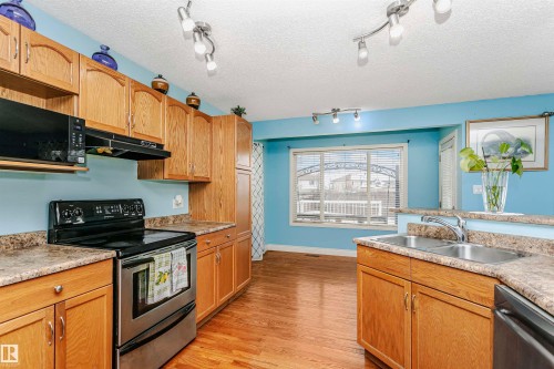 Kitchen featuring stainless steel appliances, light countertops, light wood-style floors, and a textured ceiling - 607 Windross Crescent, Edmonton, AB - Indoor Photo Showing Kitchen With Double Sink