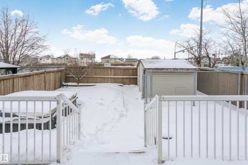 Yard layered in snow with a fenced backyard, a deck, a storage unit, and a residential view - 607 Windross Crescent, Edmonton, AB - Outdoor