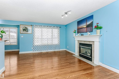 Unfurnished living room with light wood-style flooring, a tiled fireplace, and a textured ceiling - 607 Windross Crescent, Edmonton, AB - Indoor Photo Showing Living Room With Fireplace