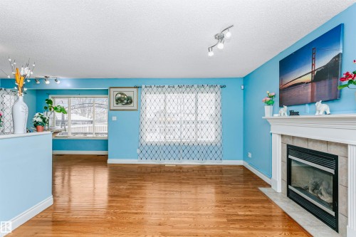 Unfurnished living room with rail lighting, a textured ceiling, light wood-type flooring, and a fireplace - 607 Windross Crescent, Edmonton, AB - Indoor Photo Showing Living Room With Fireplace