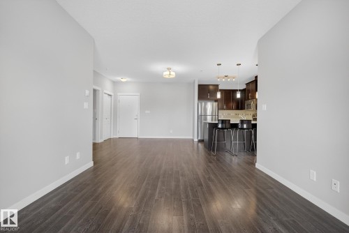 Unfurnished living room with dark wood-style flooring and baseboards - 206 812 Welsh Drive, Edmonton, AB - Indoor