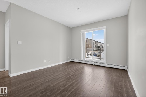 Unfurnished room featuring a baseboard radiator and dark wood finished floors - 206 812 Welsh Drive, Edmonton, AB - Indoor Photo Showing Other Room