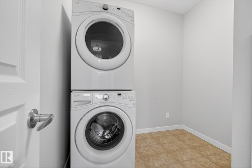 Laundry room with stacked washer and dryer and light tile patterned floors - 206 812 Welsh Drive, Edmonton, AB - Indoor Photo Showing Laundry Room