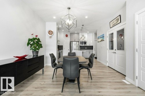Dining room with light wood-type flooring and a chandelier - 8018 Kiriak Link, Edmonton, AB - Indoor Photo Showing Dining Room